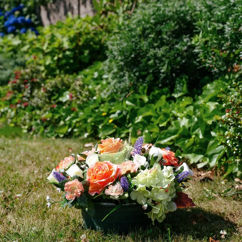 Composition florale funéraire de deuil posée sur une pelouse verte.