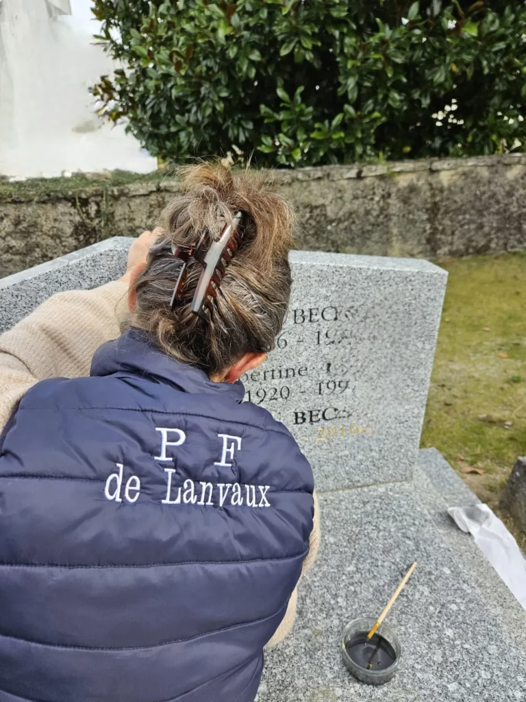Professionnel en rénovation de gravure funéraire en action au cimetière.