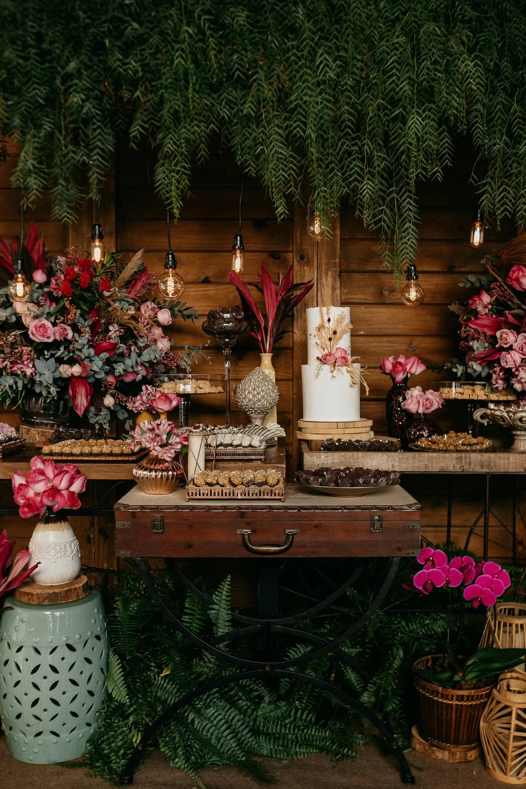 Buffet de réception funéraire raffiné avec bouquets, gâteaux et lumières.